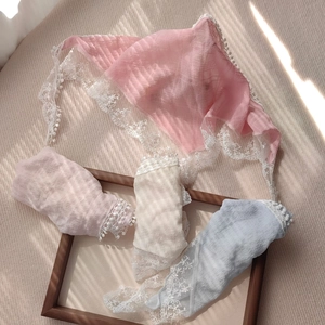 Detailed close-up of lace-trimmed triangular headscarves in pastel shades with soft shadows