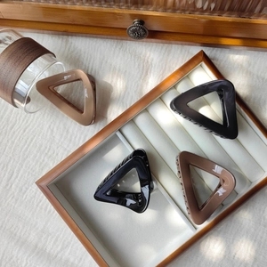 Detail of geometric triangle hair claws in beige brown and black on jewelry tray