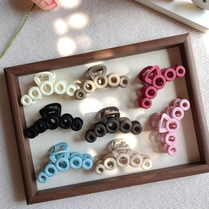 Detailed set of 8 matte hair claws in various colors on a wooden tray with soft lighting