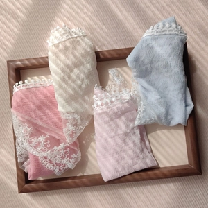 Detailed view of pastel floral lace panties in a wooden tray with elegant shadow lighting