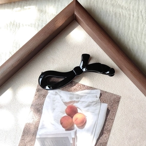 Détail d'une pince banane noire brillante au design torsadé pour queue de cheval haute