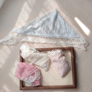 Detailed close-up of textured lace-edge headscarves in soft pastel blue, beige, and pink tones