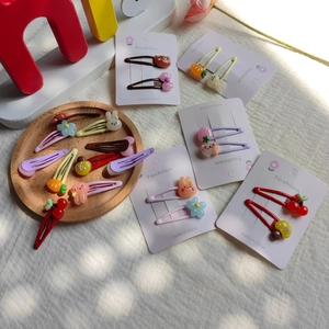 Close-up of cute cartoon resin hair clips with bunny and floral charms on a white card