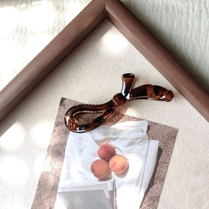 Gros plan d'une pince à cheveux banane marron au design de nœud élégant et torsadé