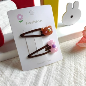 Detail view of cute brown resin bear and pink polka dot bow clips on a display card