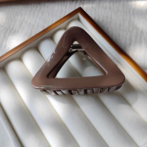 Detailed close-up of brown glossy resin triangle hair claw with non-slip metal spring