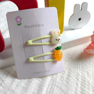 Detail of green children's hair clips featuring cute white rabbit and carrot charms