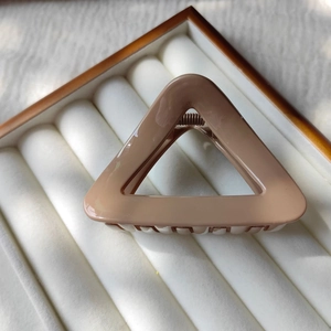 Close-up of a glossy triangle hair claw clip with a strong metal spring on a soft tray