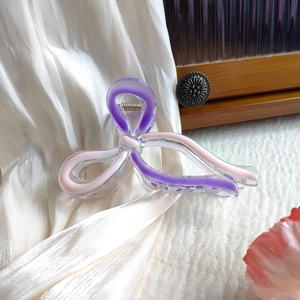 Close-up of pink and purple acrylic butterfly hair claw clip with metallic spring
