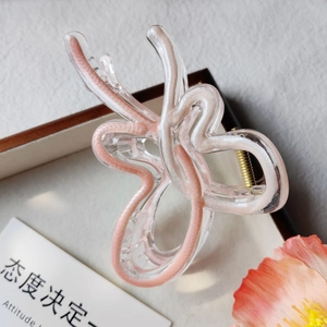 Vue macro d'une pince à cheveux papillon aux motifs ondulés roses et crème doux