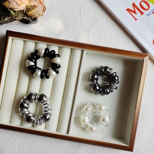 Detail view of pearl telephone wire hair ties in various metallic and resin finishes