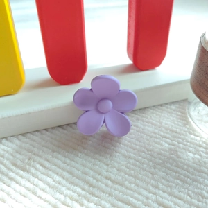 Nahaufnahme einer matten lavendelfarbenen Blumenhaarklammer auf weißem Streifenstoff