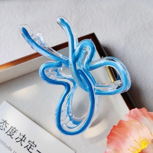 Détail de la pince à cheveux papillon bleue au design fluide avec ressort doré