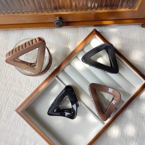 Set of 4 minimalist triangle hair claws in black and coffee brown on a wooden jewelry tray