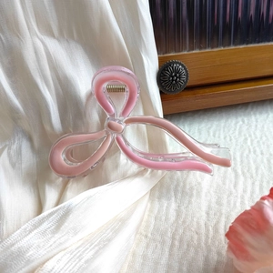 Detail of pink butterfly hair claw clip with golden metal spring on silk fabric background