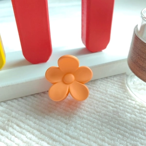 Detailansicht einer orangefarbenen matten Blumen-Haarklammer mit lebhaftem 5-Blüten-Design