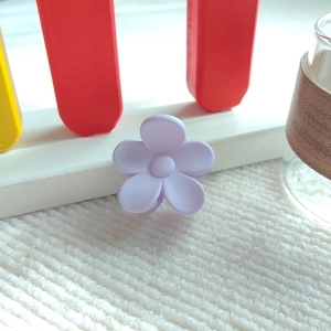Nahaufnahme einer kleinen lavendelfarbenen Blumen-Haarklammer mit mattem Finish auf Stoff