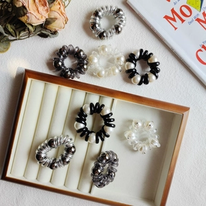 Flat lay of elegant pearl spiral hair coils in silver and smoky grey on white background