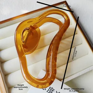 Detailed macro view of large amber jelly hair claw clip with golden metal spring