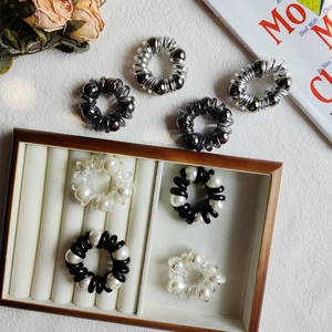 Detailed shot of assorted pearl spiral hair ties and metallic phone cord scrunchies