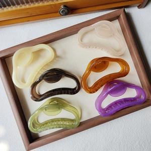 Close-up of six translucent jelly color cloud hair claws on a wooden display tray