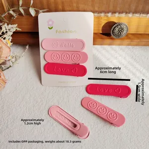 Dettaglio di fermagli per capelli opachi color caramello con scritte Hello e Love su carta