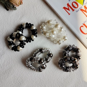 Set of spiral telephone wire hair ties with pearl and metallic bead accents on flat lay