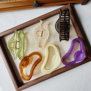 Collection of large matte resin hair claws in six soft pastel jelly colors on a wooden tray