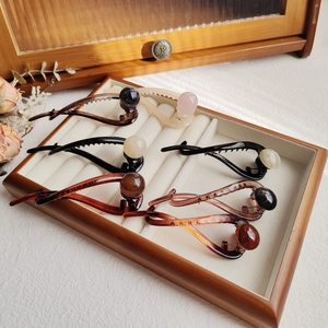 Close-up of minimalist glossy hair clips with marble-textured beads in a wooden box