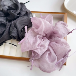 Detail von schwarzen und lila Organza-Haargummis mit eleganten Schleifen auf einem Tablett