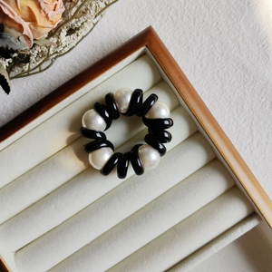 Detail of elegant pearl telephone wire hair tie on soft grey velvet display tray with flowers