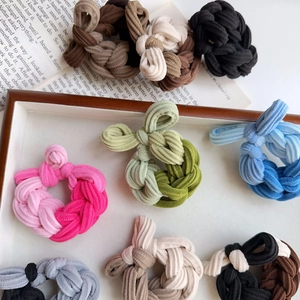 Close-up of multicolored braided hair ties with textured fabric on a wooden tray