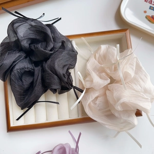Detail von Organza-Haargummis mit Schleife in Schwarz und Beige auf Samttablett