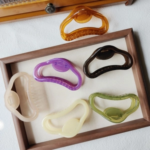 Set of six large jelly-colored cloud hair claws in translucent acrylic on a wooden tray
