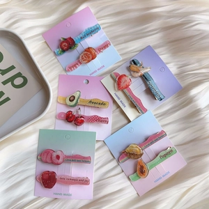 Macro view of transparent glitter acrylic fruit hair clips with handmade paper card