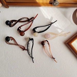 Detailed view of six resin hair claws with decorative pearls in brown and beige tones