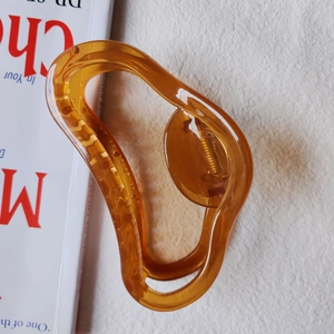 Macro shot of amber resin hair claw clip with golden metal spring on white background