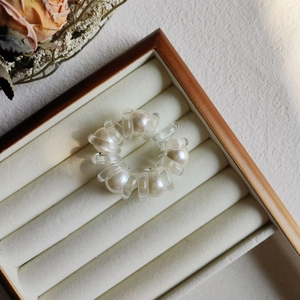 Detail view of pearl spiral hair tie in a white velvet box with floral decoration