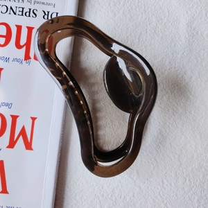 Detail of a large translucent coffee brown shark clip showing smooth curves and inner spring