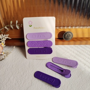 Dettaglio di fermagli opachi viola con testo Hello e Love in rilievo su cartoncino