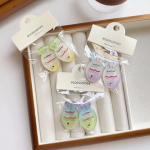 Close-up of translucent gradient fish hair clips on display cards in a velvet jewelry tray