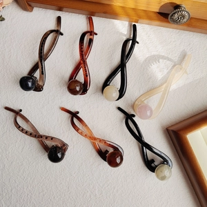Macro detail of twisted hair clips in multiple colors with elegant pearl embellishments