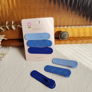 Dettaglio di fermagli per capelli blu opachi con scritte Hello Love e icone cuore