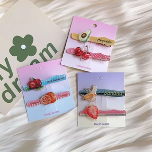 Close-up of glitter acrylic fruit hair clips including cherry and strawberry designs