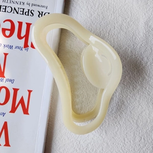 Macro detail of large cream jelly-colored claw clip with wavy cloud shape design