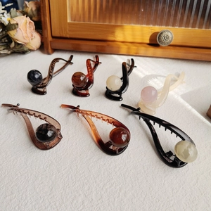 Detail of coffee-colored banana hair clips with decorative pearls and anti-slip teeth