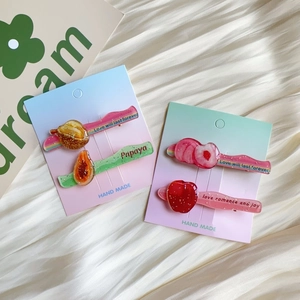 Detail of glitter acrylic fruit hair clips with durian and papaya shapes on display cards