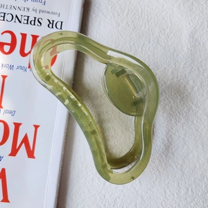 Macro view of a large translucent grass green jelly claw clip with wavy resin design