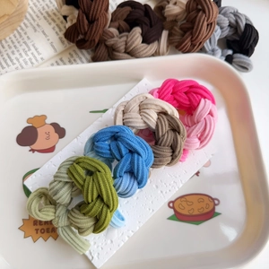 Close-up of multicolored braided high-elastic hair ties displayed on a tray