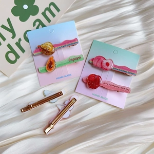 Detailed view of glitter resin fruit hair clips with colorful wave edges and metal base